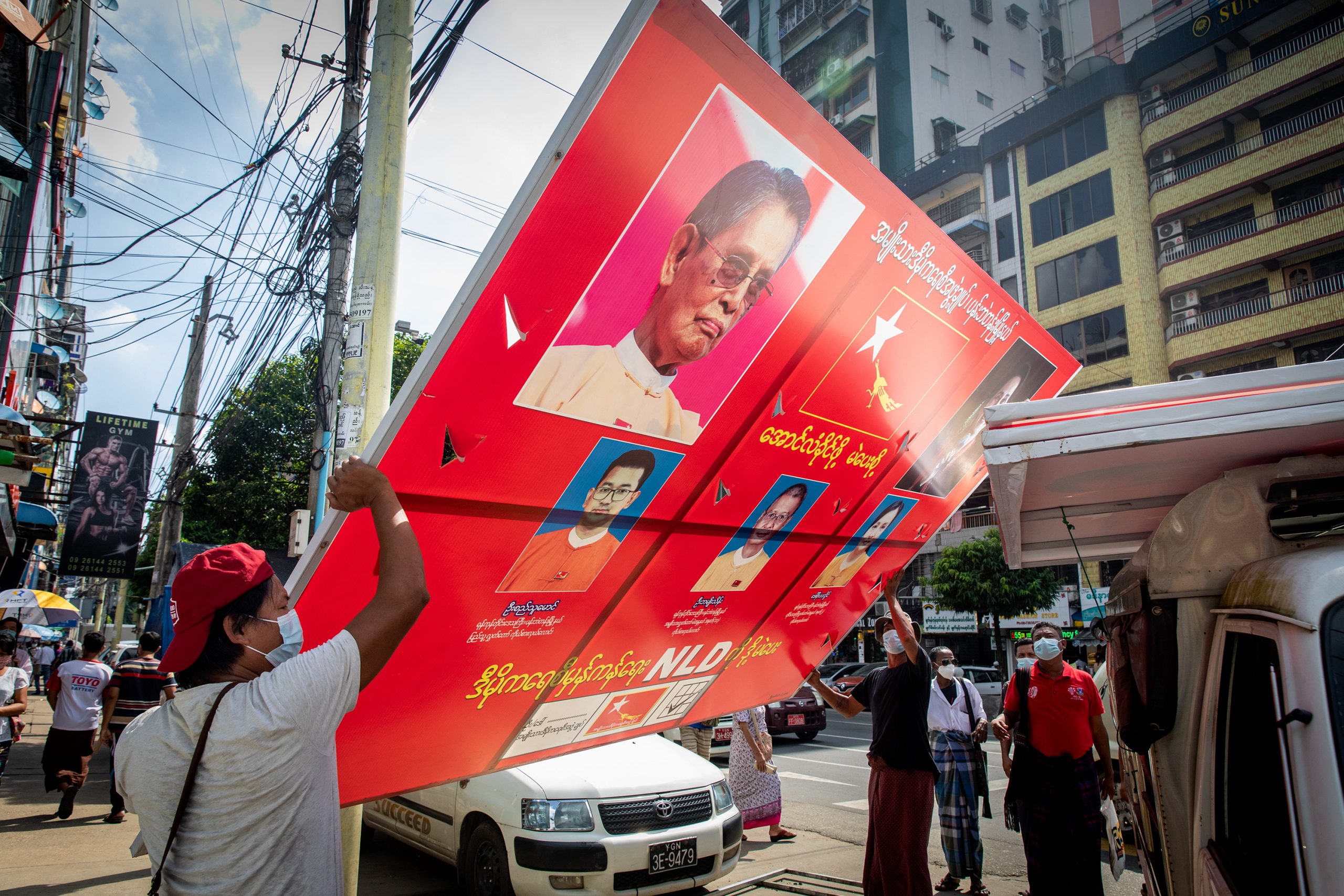 Workers in Yangon remove an NLD campaign poster ahead of the 2020 election, which the NLD won in a landslide. (Frontier)