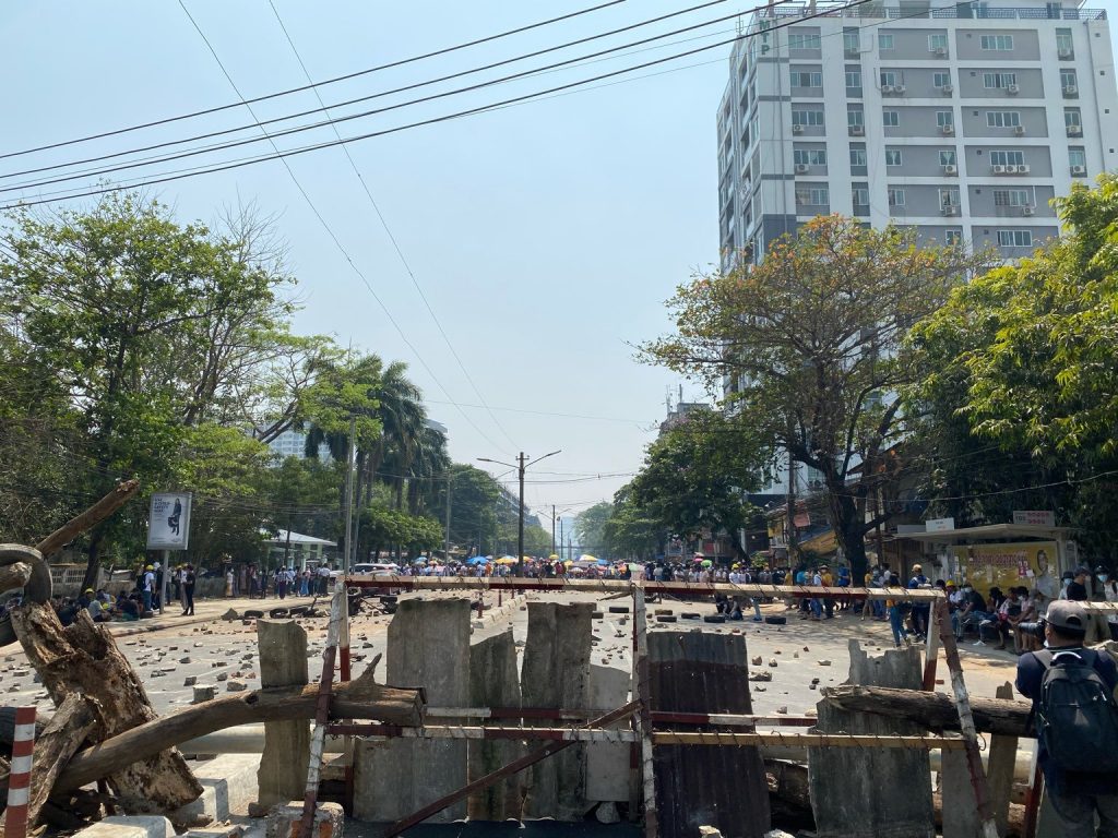 A line of police is seen over a barricade in Yangon on February 28. (Frontier)