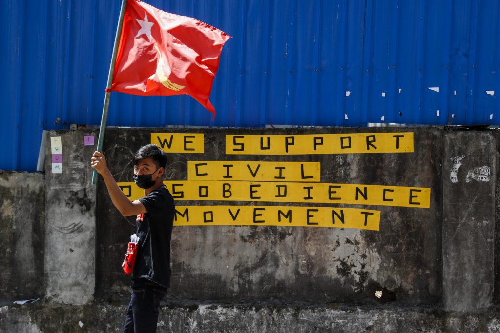 A protester waves a National League for Democracy flag in Yangon. (Frontier)