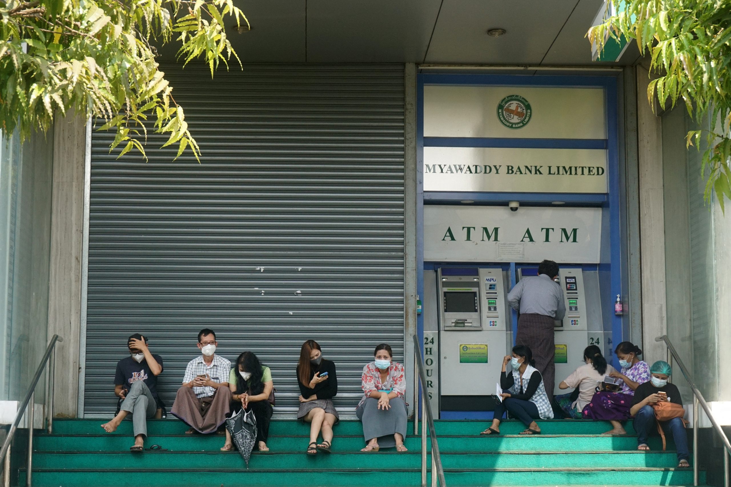 People wait to withdraw money from an ATM outside a branch of Myawaddy Bank in Yangon on February 23. (AFP)