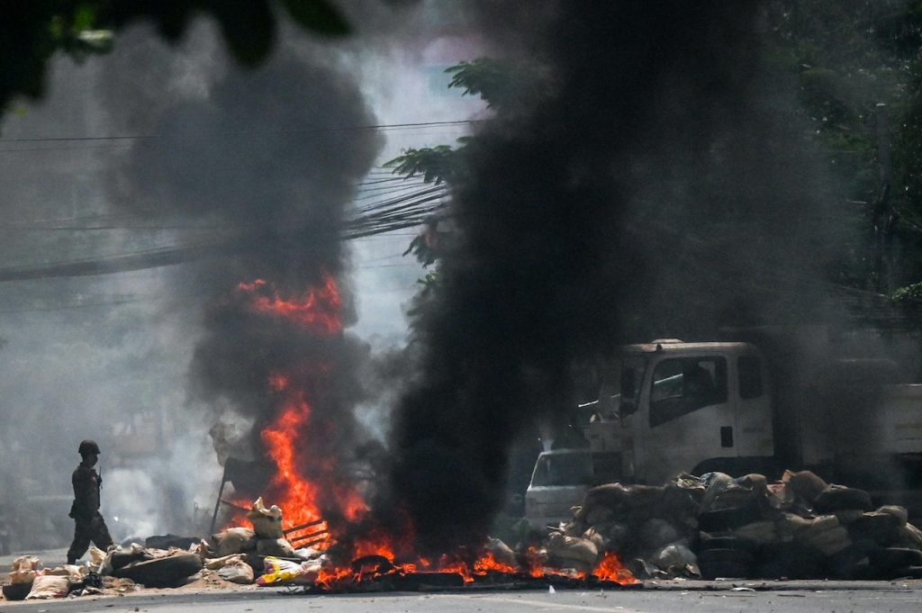Soldiers set on fire barricades, which had been erected by protesters demonstrating against the military coup, in attempt to clear the road of obstructions in Yangon on March 19. (AFP)