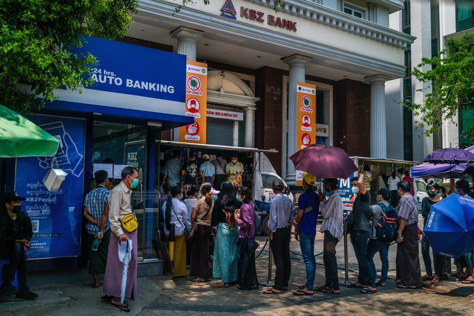 Customers queue at a KBZ Bank ATM on March 22. Myanmar's largest private bank has reopened just five of its 144 Yangon branches, according to its website, leaving customers reliant on mobile banking and ATMs. (Frontier)