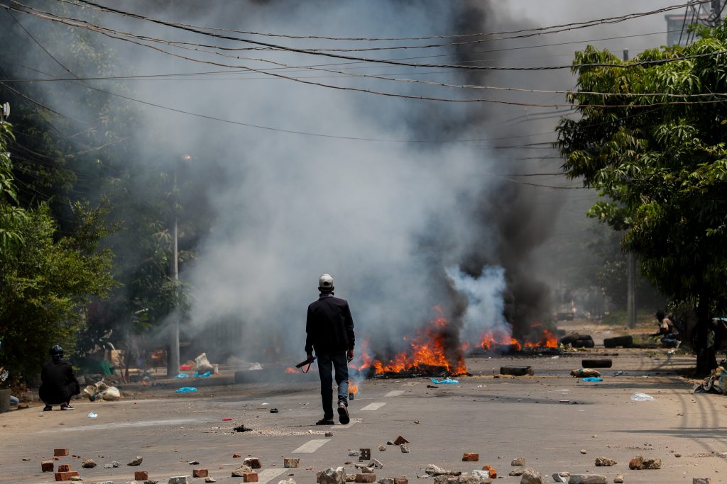 A protester in Yangon's Thaketa Township walks along a smoke-filled road earlier today. (Frontier)