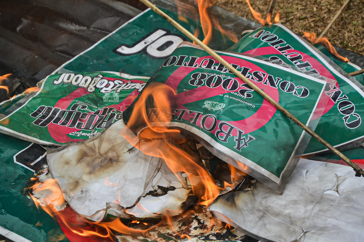 Signs about the 2008 Constitution are burnt during a demonstration by supporters Karen National Union supporters against the military coup in Kawkareik Township, eastern Karen State on April 2. (AFP)