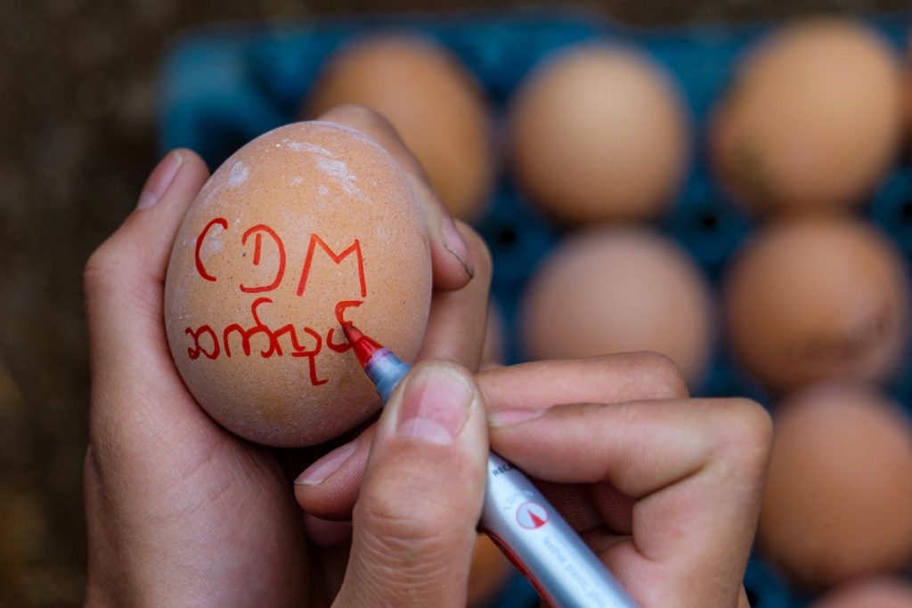 A protester writes a message of support for the Civil Disobedience Movement onto a boiled egg during an anti-coup demonstration in the Shan State capital Taunggyi on Easter Sunday, April 4. (AFP)