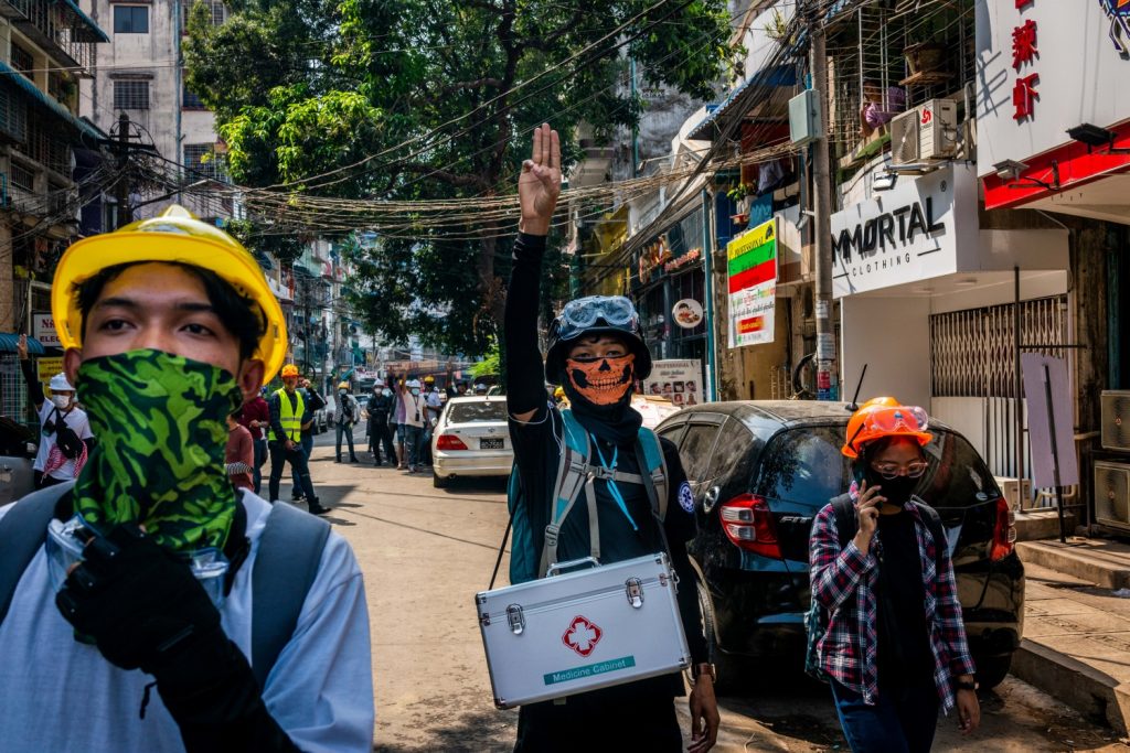 A rescue volunteer (centre) with a medical box raises the three-finger salute while serving at a protest in Yangon on March 3. (Frontier)