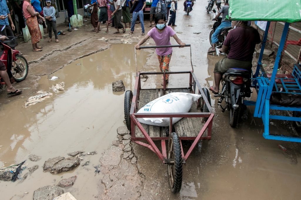 A girl pushes a wheelbarrow with a bag of rice from the World Food Programme in a poor neighbourhood on the outskirts of Yangon on May 21. (AFP)