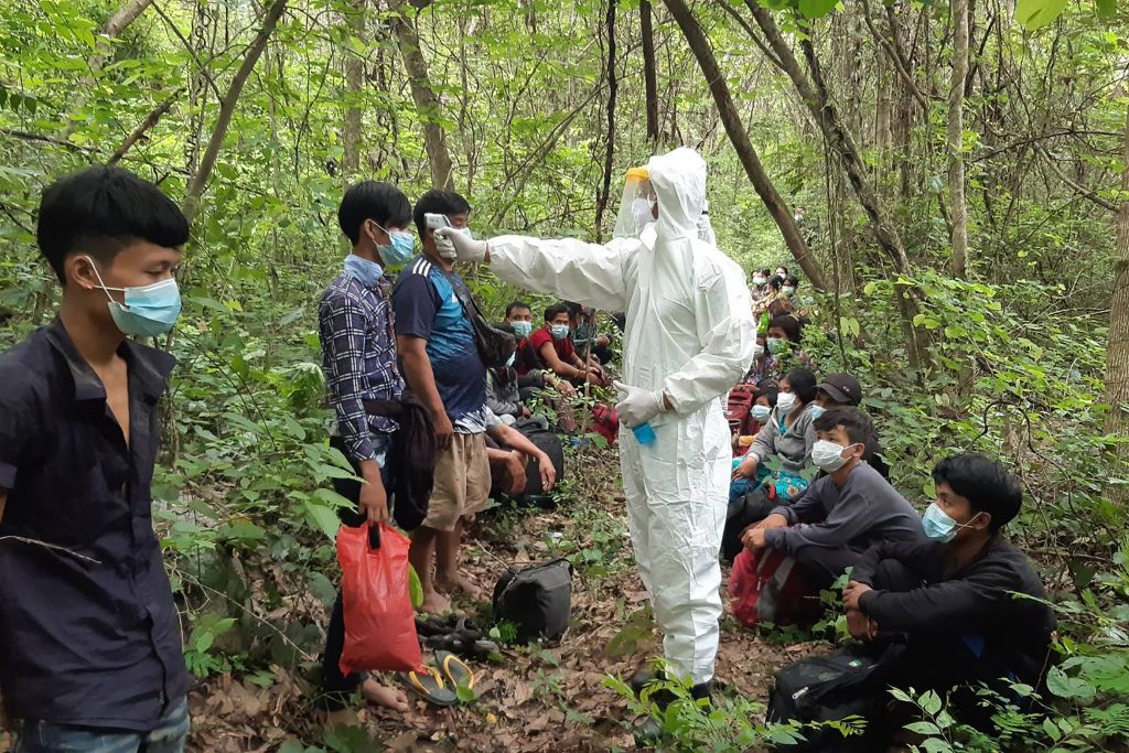 Thai military personnel in personal protective equipment (PPE) check the temperatures of migrants from Myanmar detained near the border in Prachuap Khiri Khan province on May 9.(APF/Royal Thai Army)