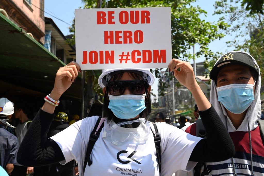 A woman at an anti-coup demonstration in Yangon on March 8 holds up a placard calling for public sector workers to join the Civil Disobedience Movement. (AFP)