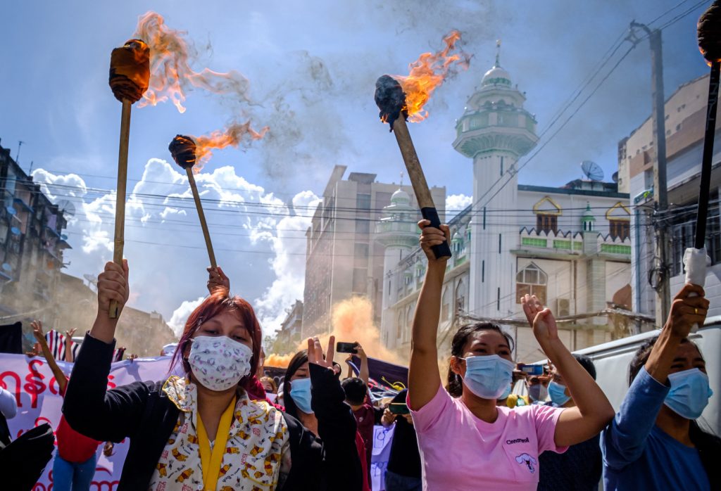 Women carry burning torches as they march during a demonstration against the military coup in Yangon on July 14. (AFP)