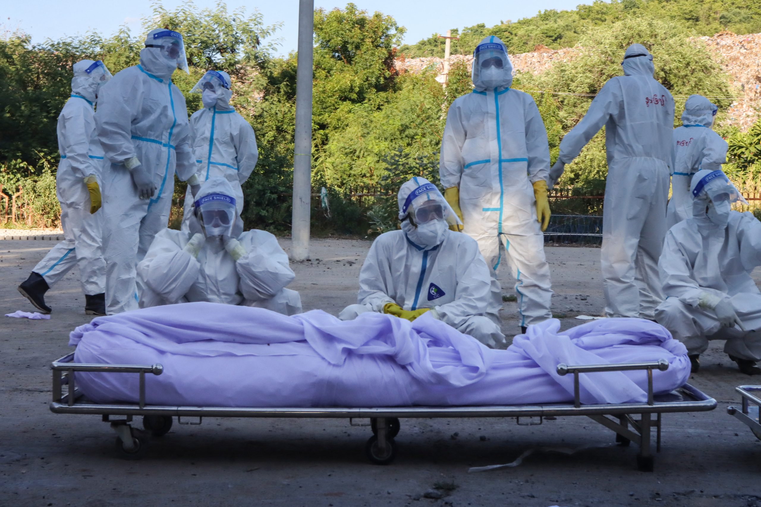 Volunteers wearing personal protective equipment in front of bodies of people who died from the Covid-19 coronavirus during their funeral at a cemetery in Mandalay on July 14, 2021. (AFP)