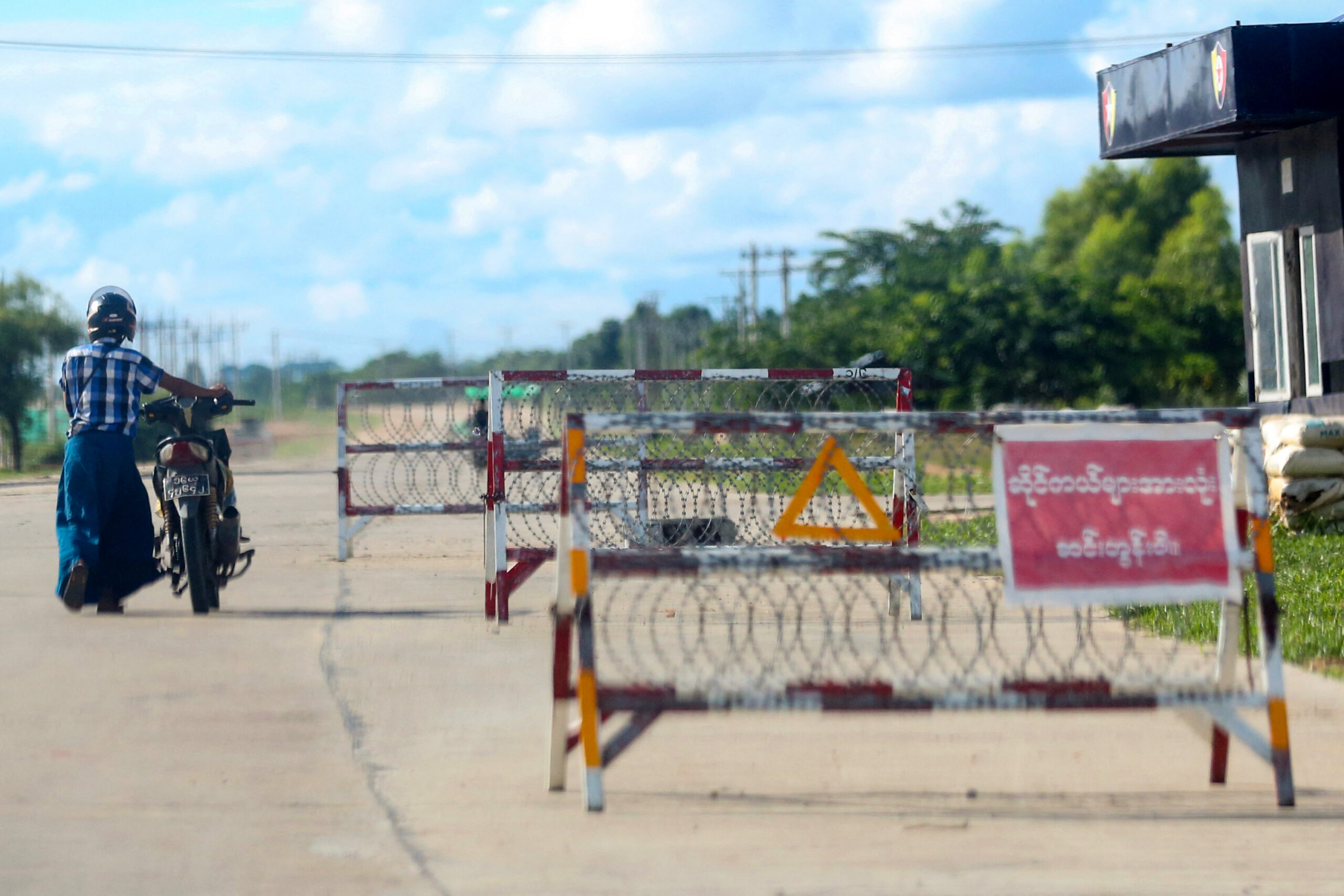 A motorist pushes his motorcycle past a security checkpoint in Nay Pyi Taw. (AFP)