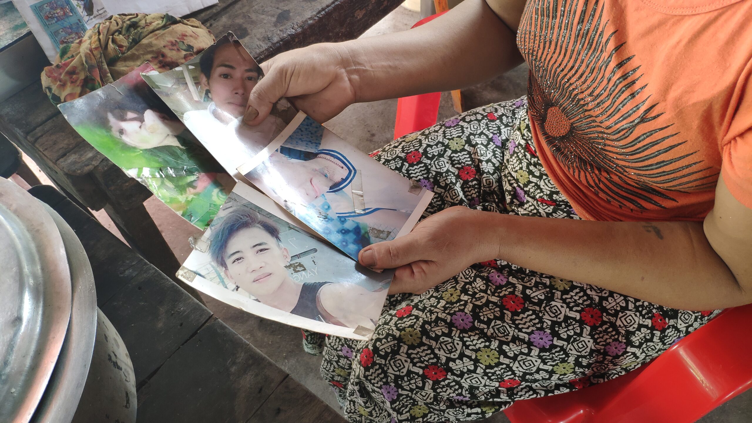 Daw San San Aye shows photographs of her four sons who are being held in separate prisons across the country. (Frontier)