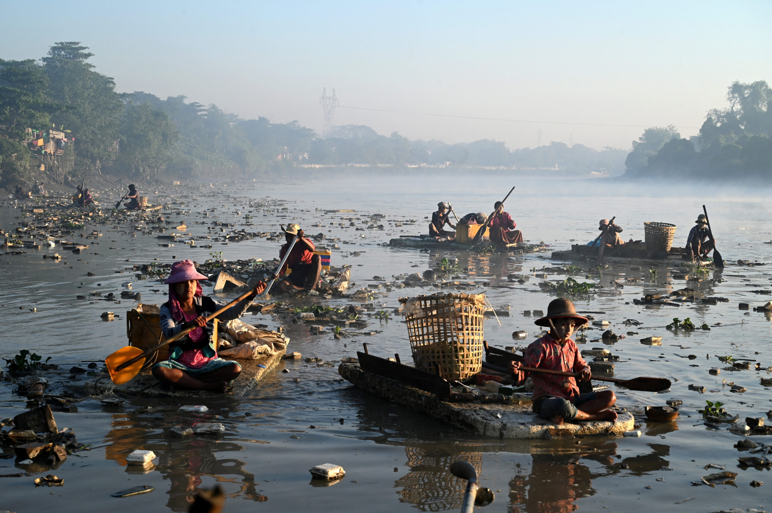Waste collectors paddle polystyrene boats while searching for plastic and glass to recycle in Pazundaung Creek in Yangon. (Sai Aung | AFP)