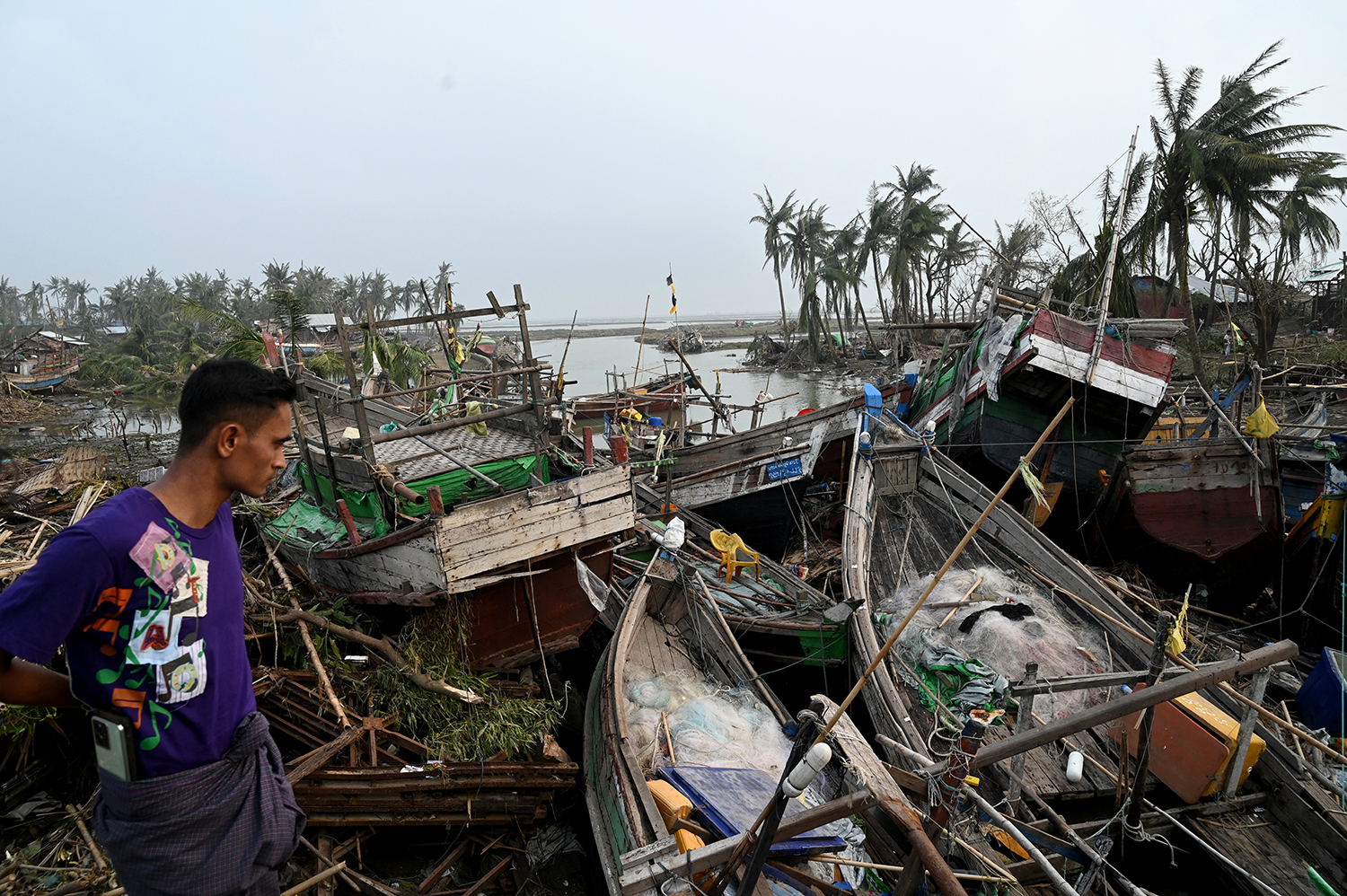 A local resident looks at broken boats in Sittwe, in Myanmar's Rakhine State, on May 15, 2023, after cyclone Mocha made a landfall. (AFP)