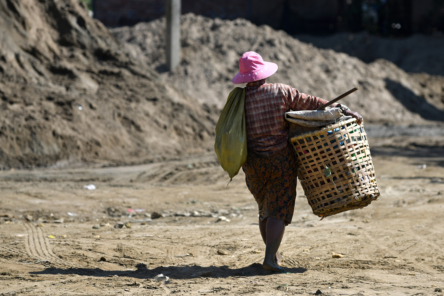 A waste collector carries a basket of plastic and glass to recycle by Pazundaung Creek in Yangon on January 14, 2023. (AFP)