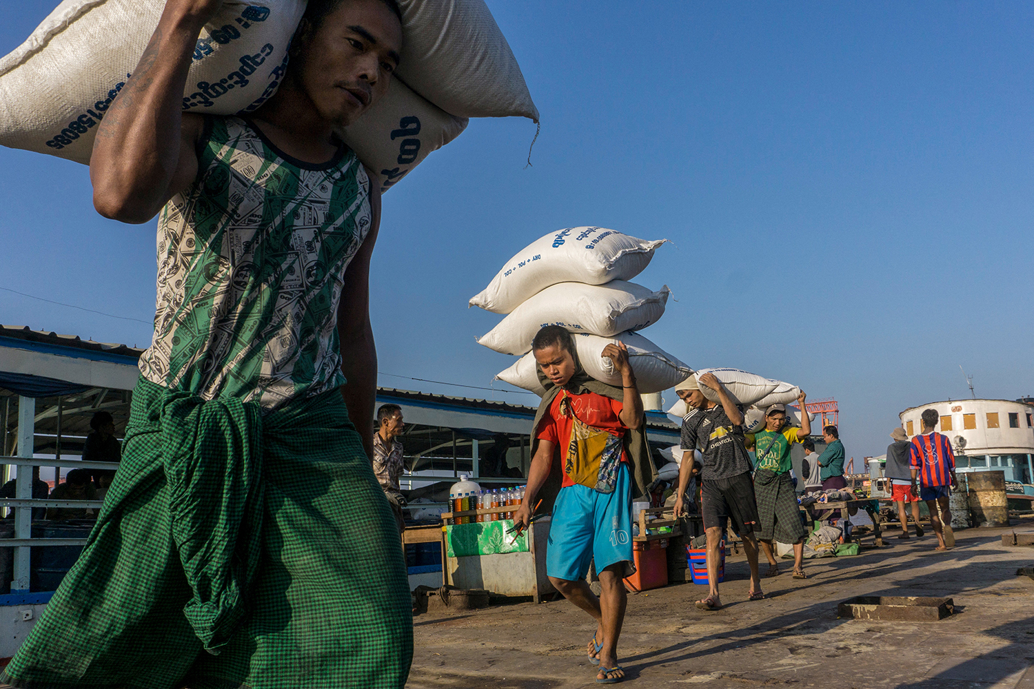 Labourers unload sacks of rice from a ship at a jetty in Yangon on February 3, 2021. (AFP)