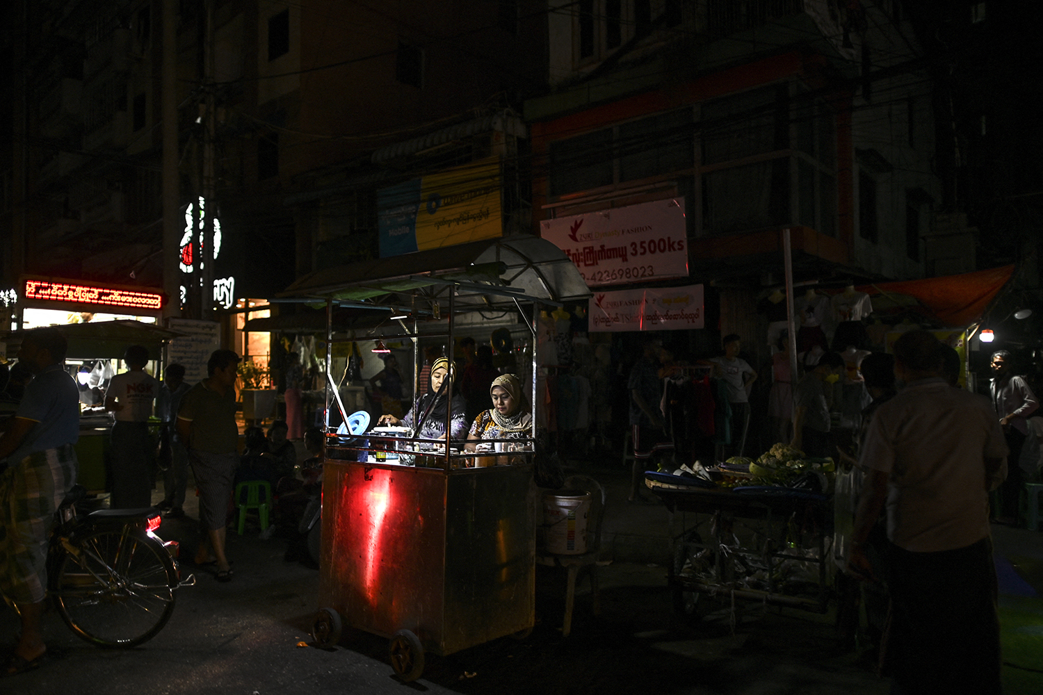 Street food vendors wait for customers during a power outage in Yangon on March 3, 2022. (AFP)