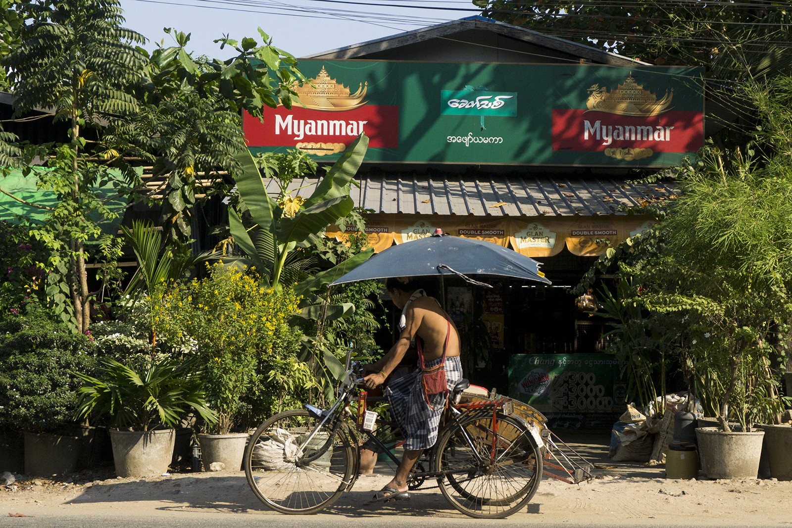 A man rides a trishaw in front of liquor shop with a billboard advertising Myanmar Beer in Yangon on February 14, 2022. (AFP)