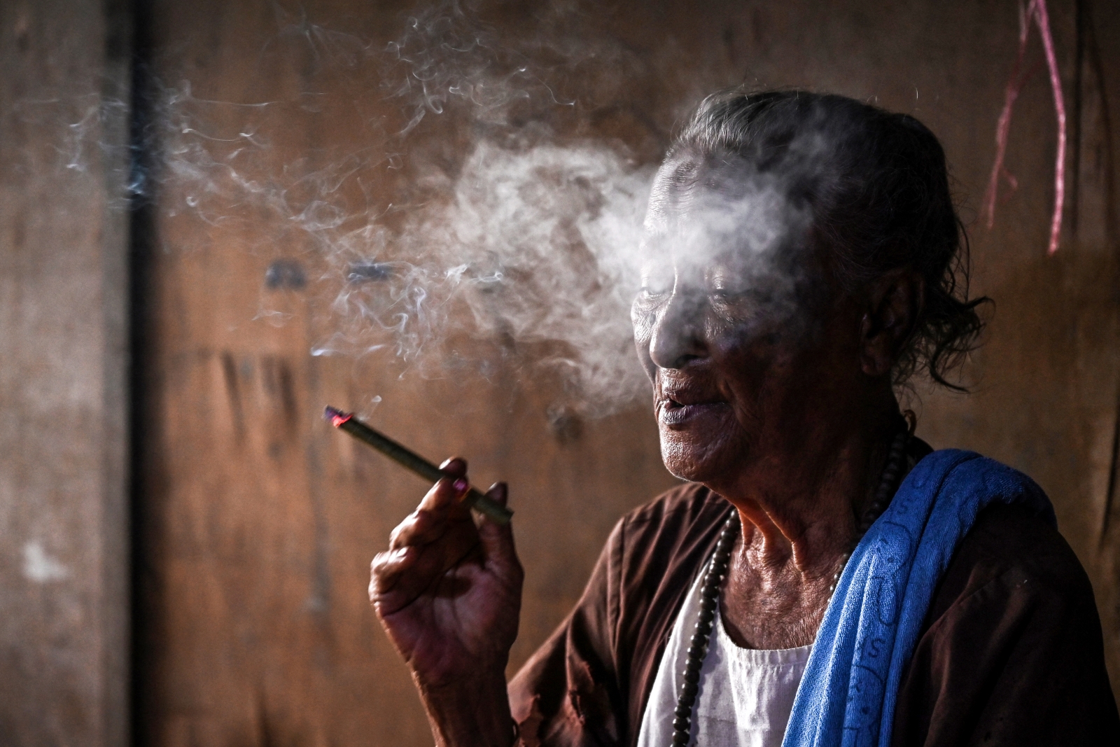 Daw Dar San Ye smokes a cheroot in her home in Yangon on September 9. (AFP)