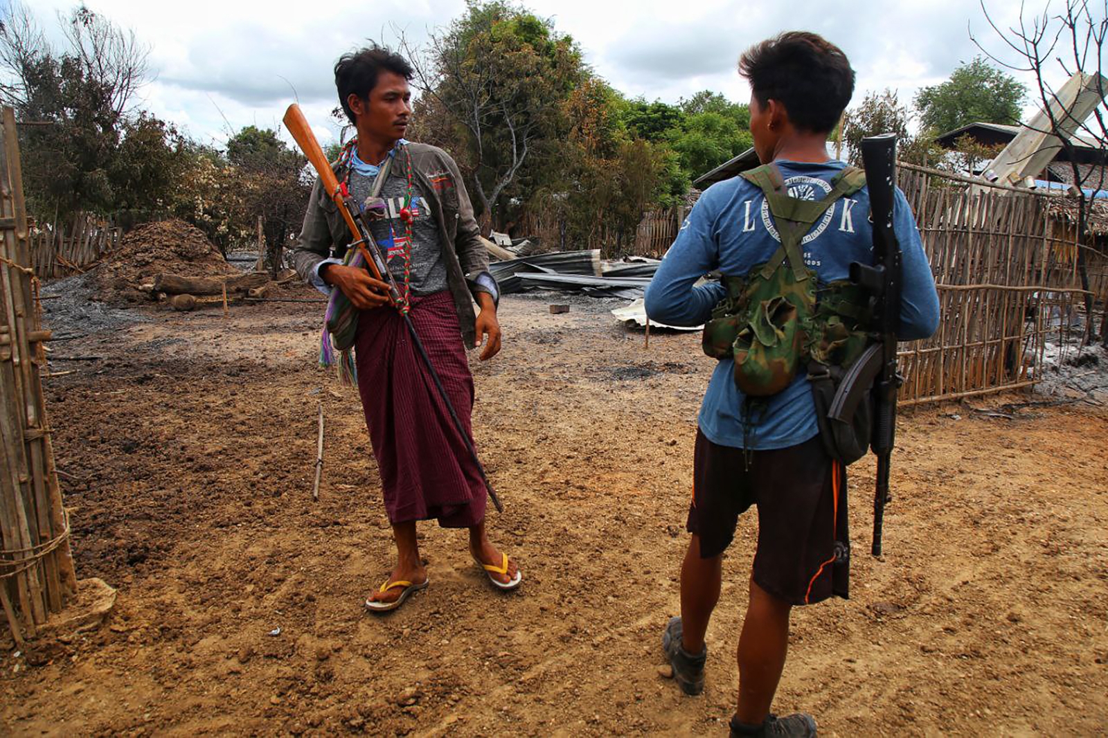 People’s Defence Force fighters stand next to burned debris after an attack by the military in a village in Sagaing Region on August 5, 2022. (AFP)
