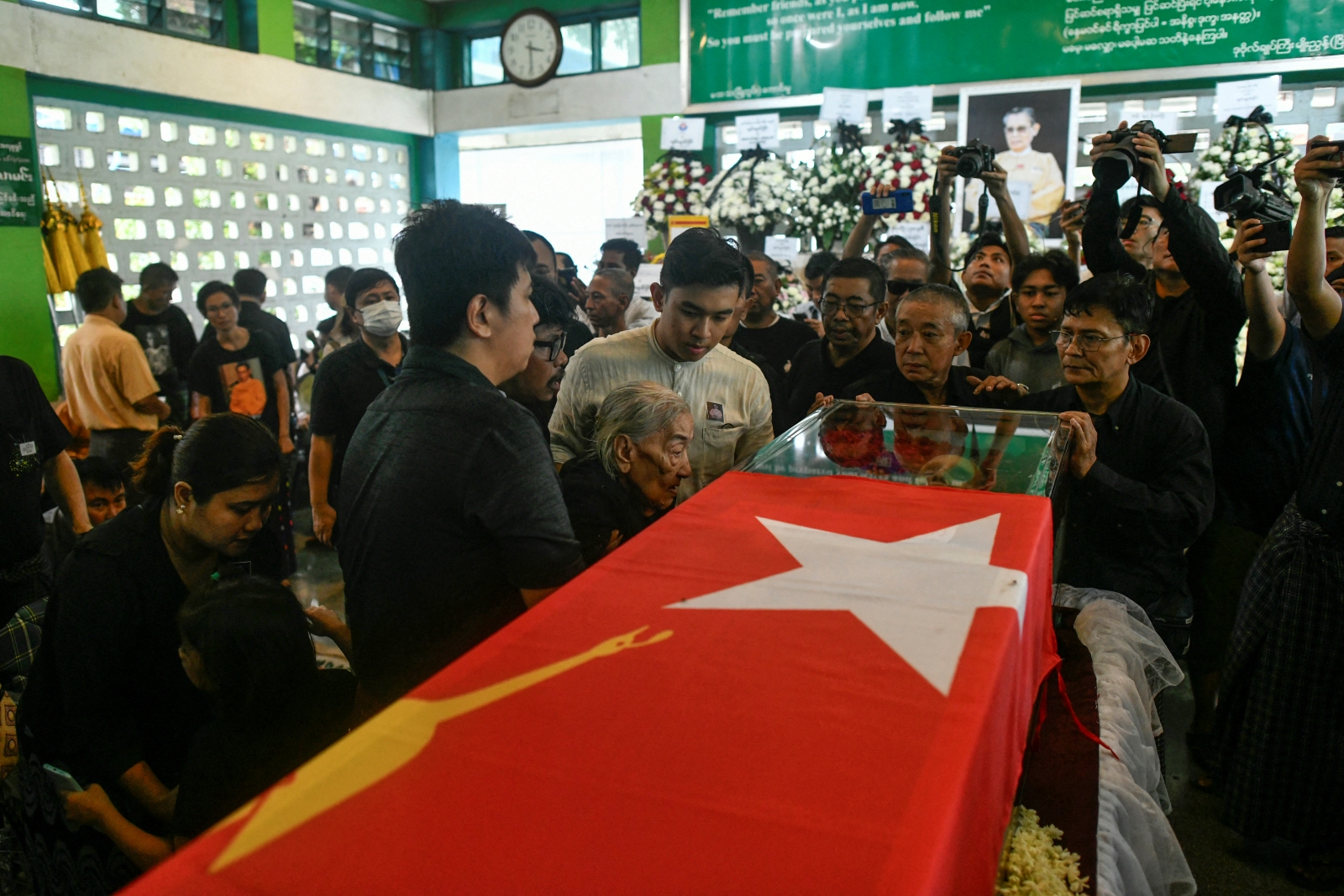Tin Moe Wai, centre, the wife of former Myanmar general and National League for Democracy co-founder Tin Oo, stands next to his coffin wrapped in the party’s flag during his funeral in Yangon on June 5. (AFP)