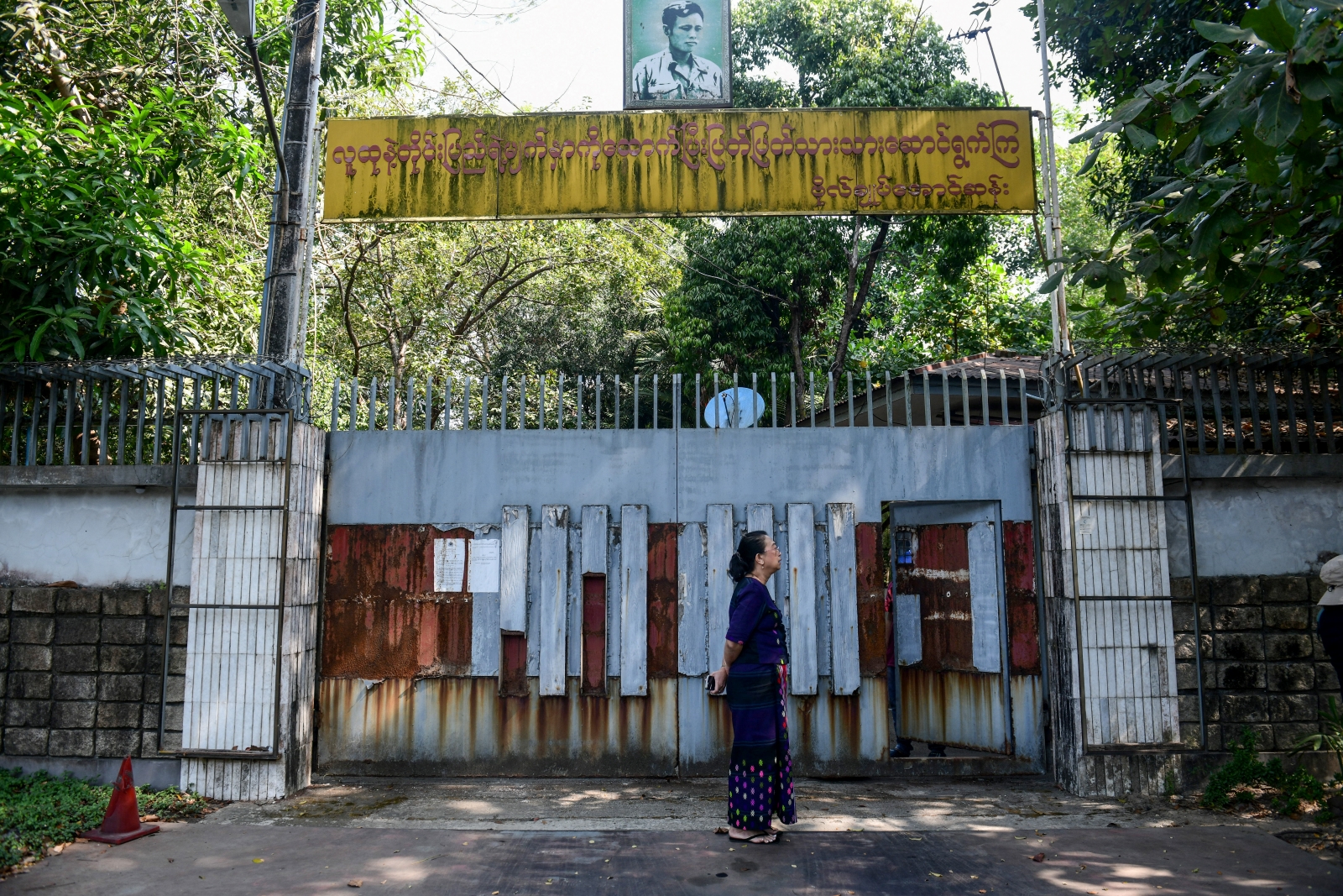 A woman stands outside the gates of the family house of deposed State Counsellor Aung San Suu Kyi in Yangon on February 5, during an attempt to auction the lakeside mansion. (AFP)