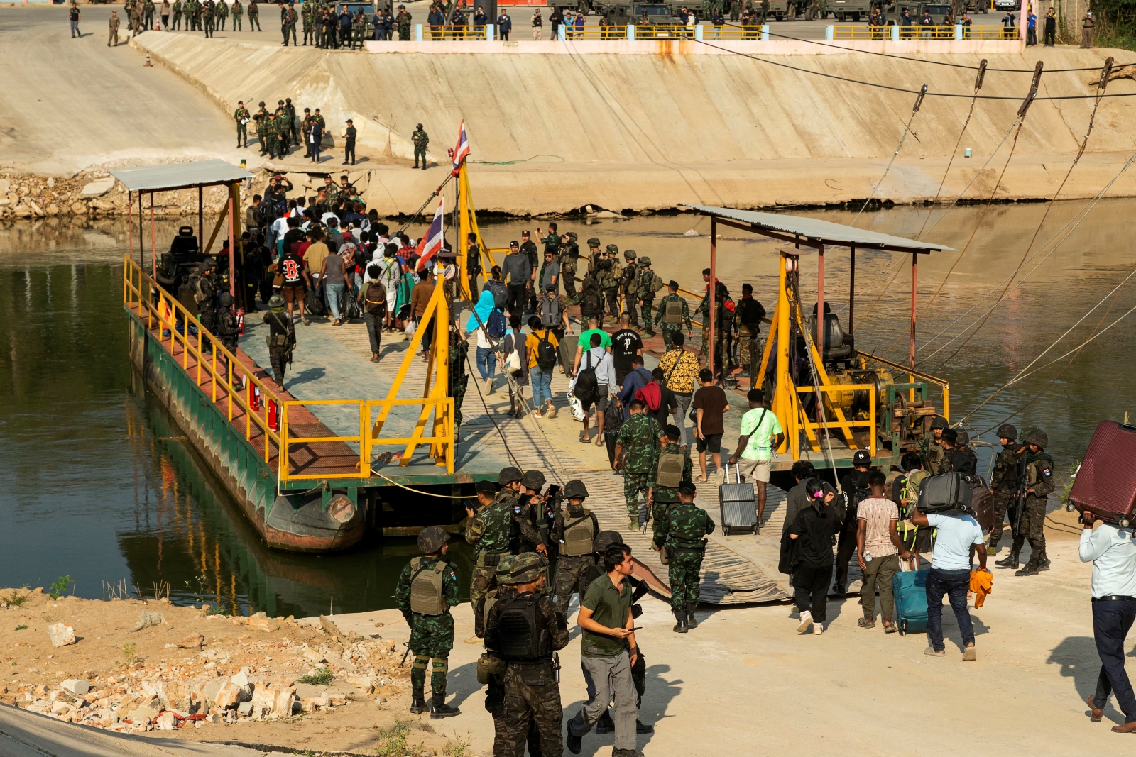 Alleged victims of cyber scam centres board a boat to cross the Moei River from Kayin State’s Myawaddy Township to Thailand, where they were met by Thai Army soldiers on February 12. (AFP)