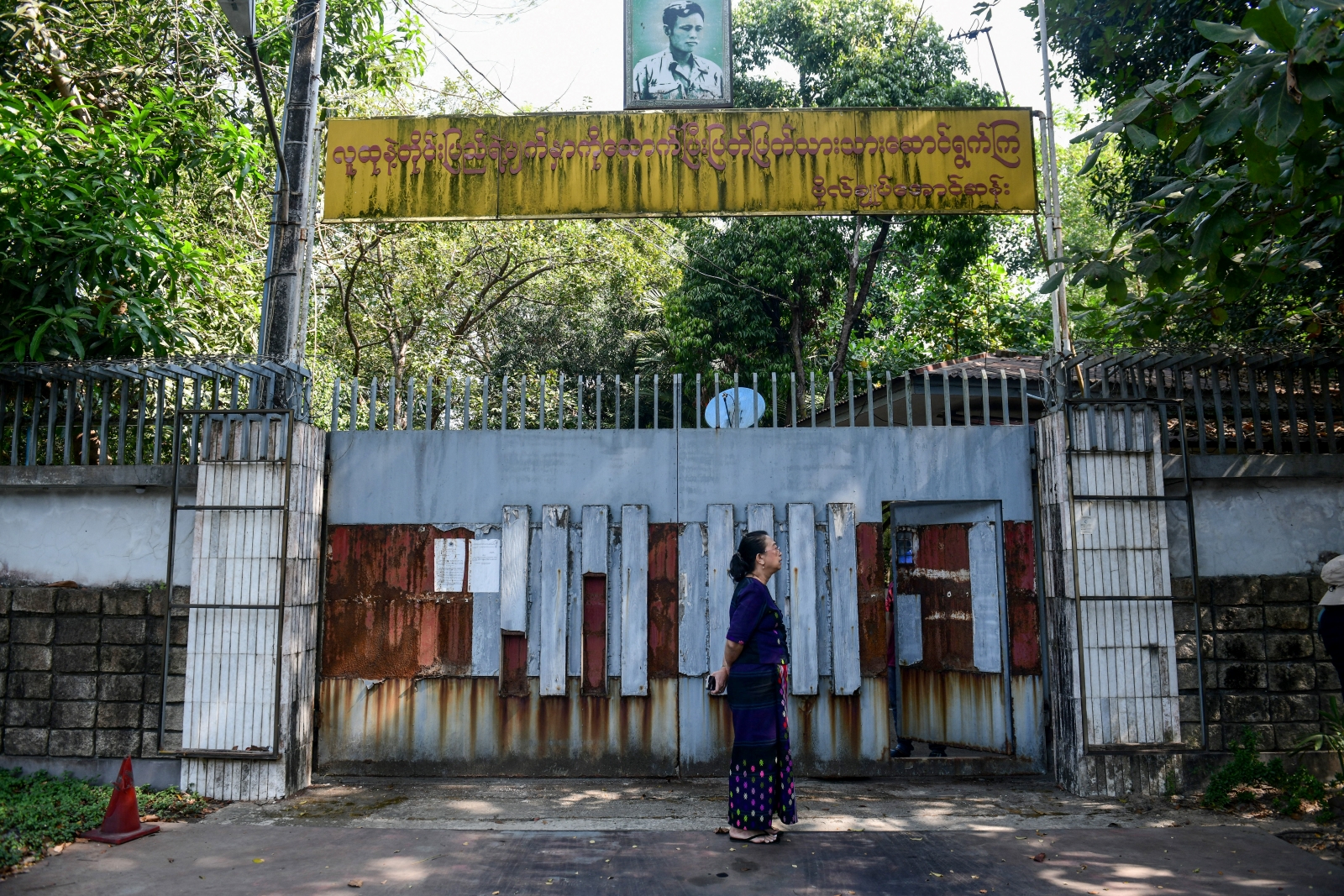 A woman stands outside the gates of the family house of detained state counsellor Daw Aung San Suu Kyi in Yangon on February 5, the day a junta court unsuccessfully tried to auction it for the third time. (AFP)