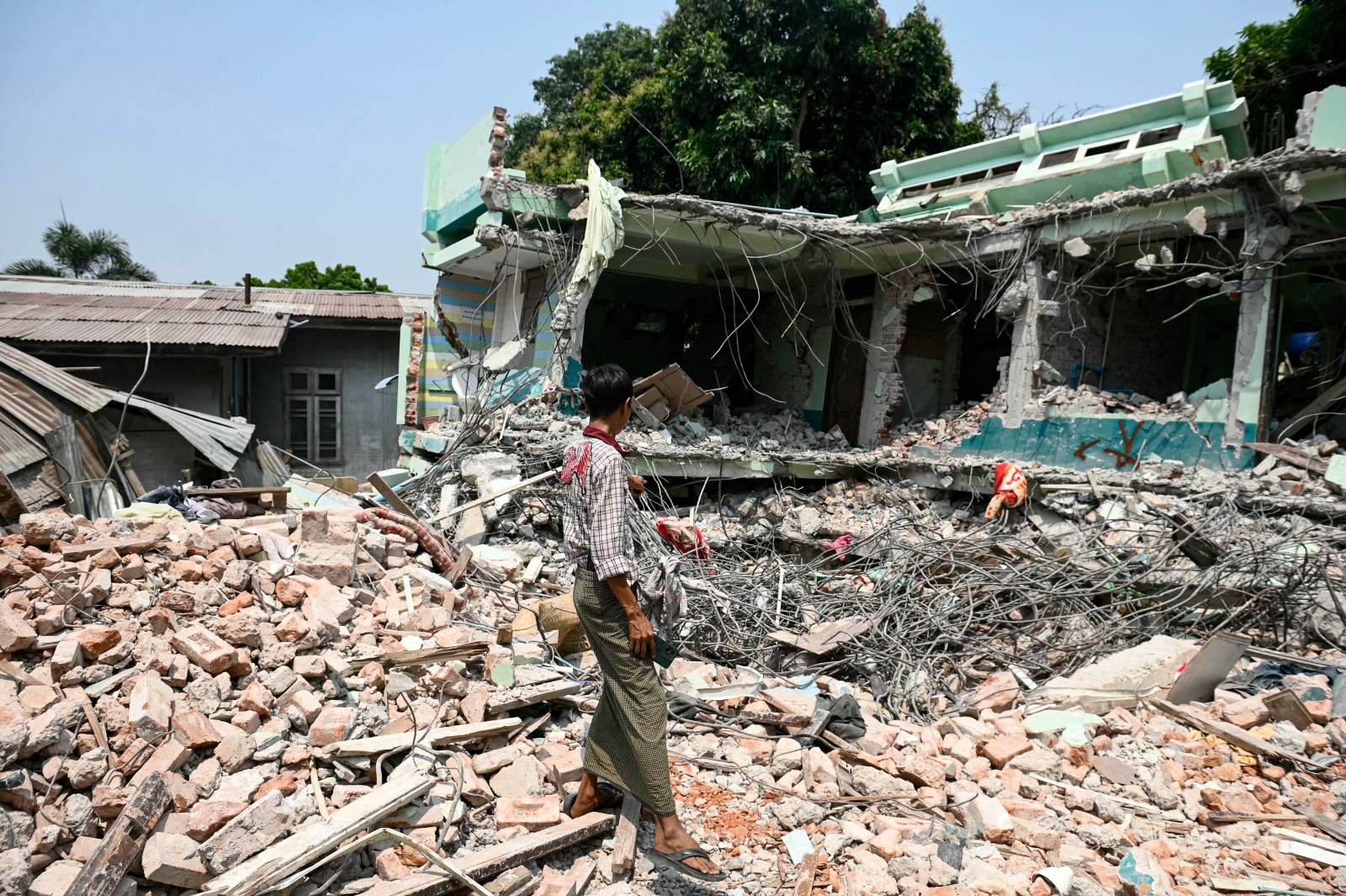 A man stands on the ruins of a collapsed hotel in Sagaing town on April 3. (AFP)