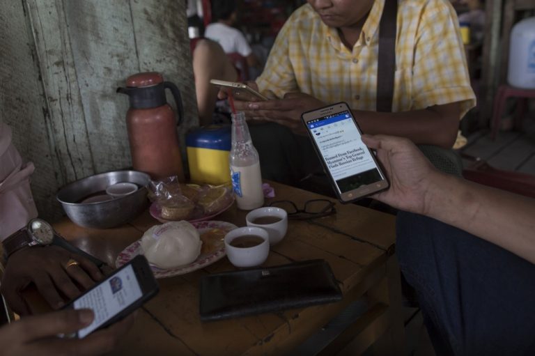 People gather at a Yangon teashop and browse Facebook on their mobile phones on August 31, 2018. (AFP)