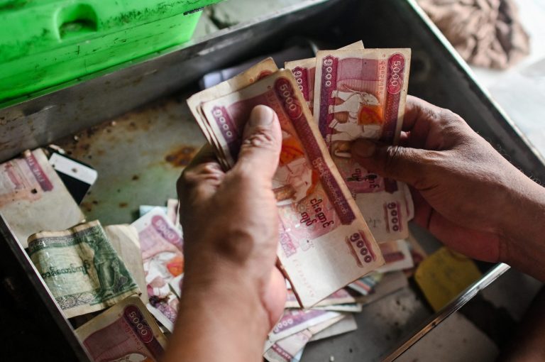 A shopkeeper counts kyat notes at his store in the Pazundaung market in Yangon on March 21, 2020. (AFP)