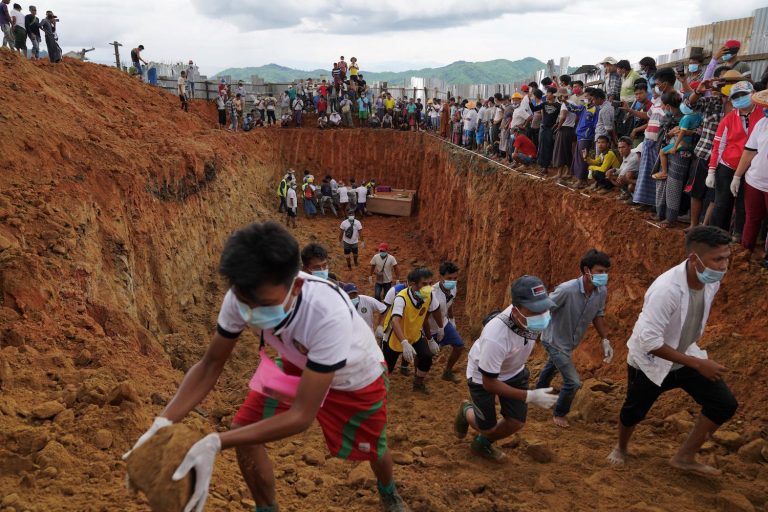 Volunteers bury bodies of miners in a mass grave while relatives look on during a funeral ceremony near Hpakant, Kachin State on July 3. (AFP)