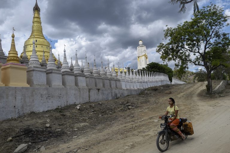 A girl rides a motorbike past a Buddhist pagoda complex in Monywa in 2020. (AFP)