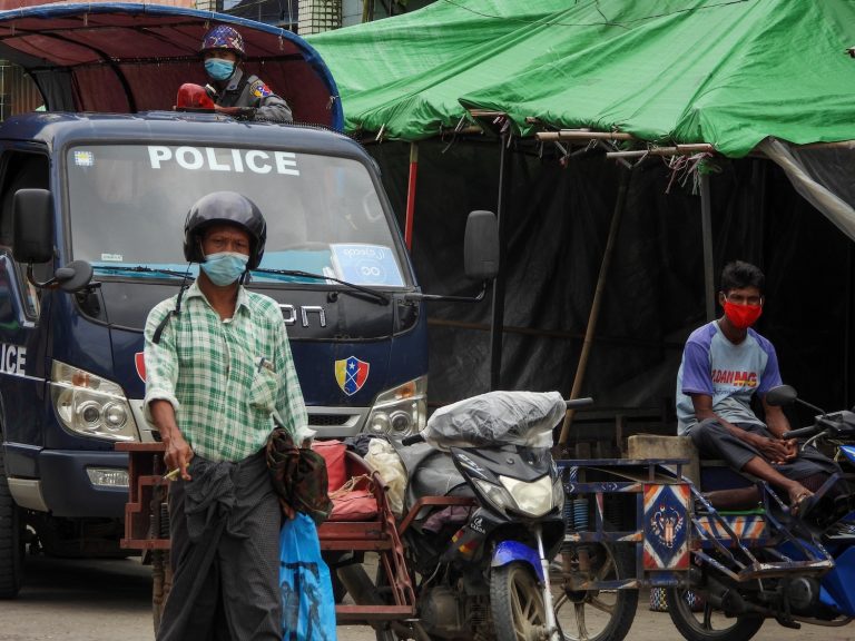 A policeman watches from a vehicle while people wear face masks in the Rakhine State capital Sittwe on August 23. (AFP)