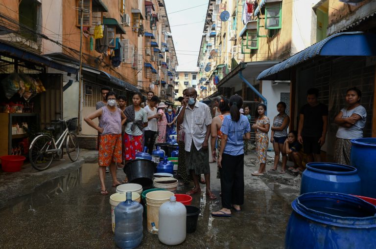 People line up to fill containers with water in Yangon on March 14, 2022, as thousands of people faced water shortages due to power outages in the city. (AFP)