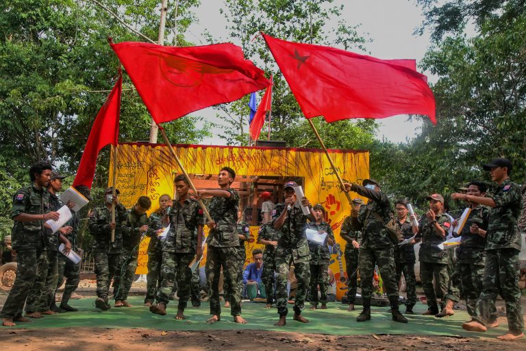Members of the Peacock Generation activist troupe, some of whom are wearing the uniforms of People's Defence Force fighters, wave student union flags during a traditional Thangyat performance in Kayin State in April last year. (AFP)