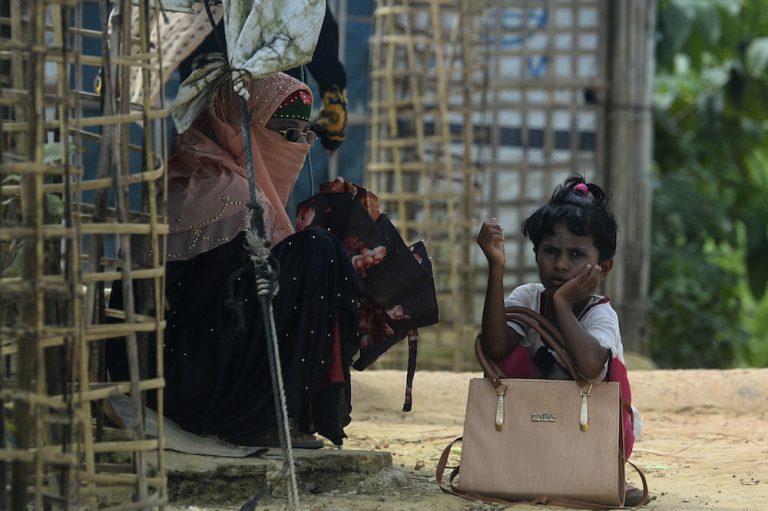 A Rohingya refugee girl waits for transportation with her mother at Kutupalong refugee camp in Ukhia on October 15, 2020. (AFP)