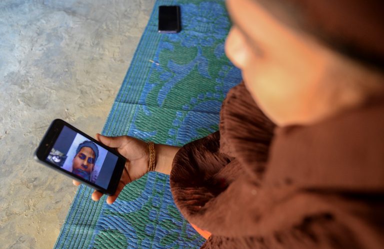 Rohingya refugee Umme Khair, who gave money to a community leader to travel to Malaysia to her husband, interacts with her spouse via video call at a makeshift shelter in Kutupalong Rohingya refugee in Bangladesh on October 13. (AFP)