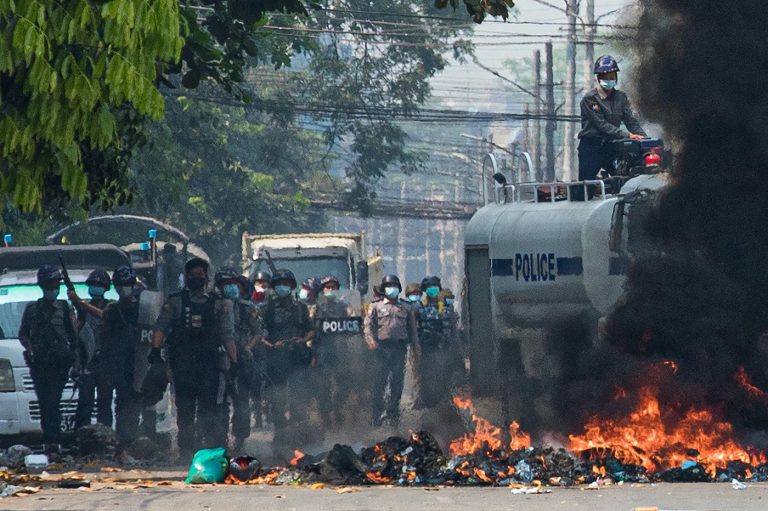 Security forces gather behind a burning barricade during a crackdown on protests against the military coup in Yangon on March 17. (AFP)