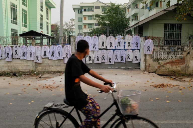 White uniforms with black ribbons hang on the fence of the Mandalay University of Medicine in 2021 in protest of the coup. (Handout / FACEBOOK / AFP) /