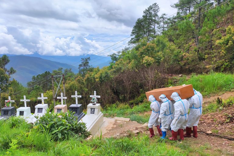 This handout photo from local media group Chinland Herald Daily News taken on June 21, 2021 and released on June 22, shows health workers in protective suit carrying a coffin bearing a body of a Covid-19 coronavirus patient during a burial at a cemetery in Falam township in western Myanmar's Chin state. (Photo by HANDOUT / CHINLAND HERALD DAILY NEWS / AFP).