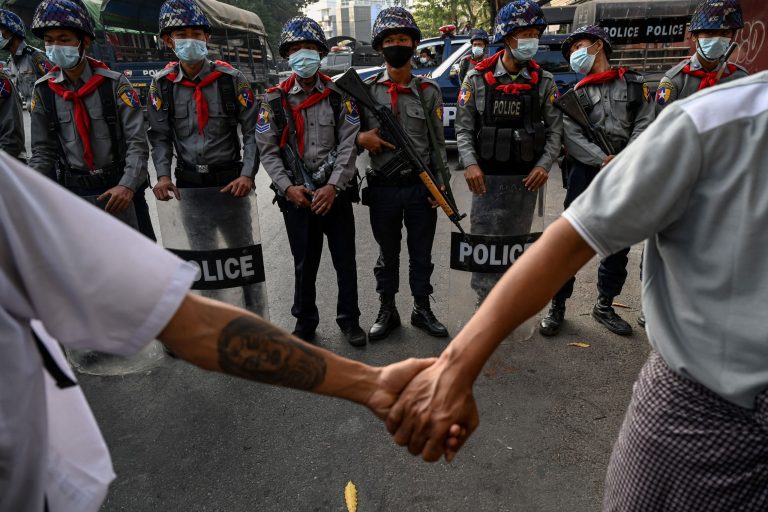 In this file photo taken on February 15, 2021 protesters hold hands to form a line in front of the police during a demonstration at the headquarters of the National League for Democracy (NLD) in Yangon. - With bars shuttered, universities empty and hook-up apps poleaxed by internet blackouts, dating got much harder in post-coup Myanmar, but young people are still finding love -- often in the heady rush of anti-junta protests. (Photo by STR / AFP)