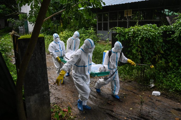 Volunteers wearing personal protective equipment carry the body of a victim of COVID-19 in Yangon at the peak of the third wave in July 2021. (AFP)