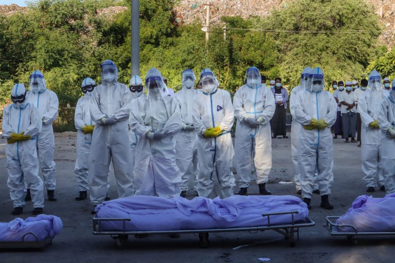 Volunteers wearing personal protective equipment pray in front of bodies of people who died from  Covid-19 at a cemetery in Mandalay on July 14, 2021. (AFP)