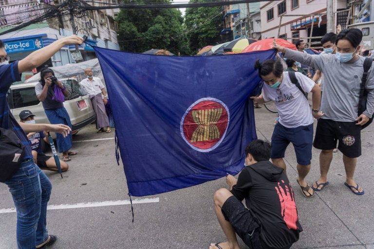 Protesters prepare to burn the flag of the Association of Southeast Asian Nations as they take part in a flash mob demonstration against the military coup in Yangon on June 14, 2021. (AFP)