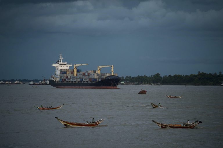 A container ship anchors along the Yangon river as traditional wooden boats ferry passengers across in 2016. (AFP)