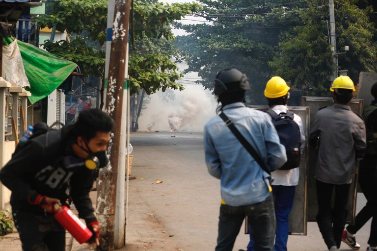 Protesters in Mandalay stand behind makeshift shields during a police crackdown this morning. (Frontier)