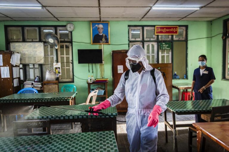 A member of Yangon City Development Committee wearing protective clothing disinfects a YCDC office in Kyimyindaing Township as part of preventative measures against the spread of COVID-19 in Yangon on 25 March. (Hkun Lat I Frontier)