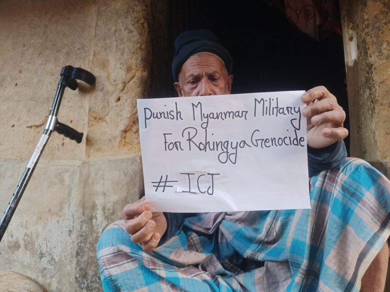 A Rohingya man holds up a sign in support of the case against Myanmar at the International Court of Justice in February. (Frontier | Md Jamal)